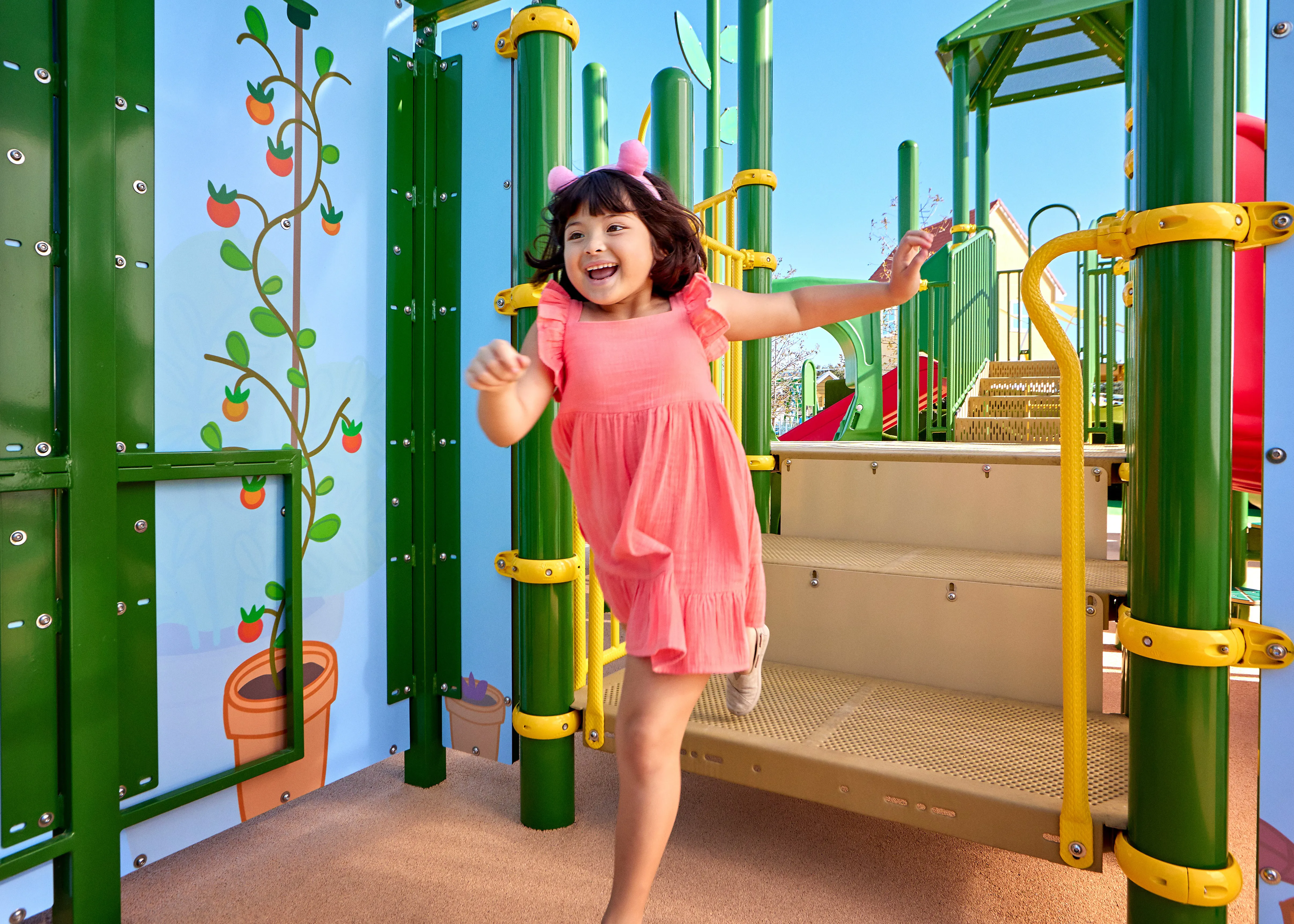 Una niña juega en la atracción de la Casa del Árbol de Peppa en Peppa Pig Theme Park en Dallas Fort Worth. Ella sube y explora la colorida y interactiva casa del árbol, sonriendo mientras disfruta del juego divertido e imaginativo en el animado entorno del parque.