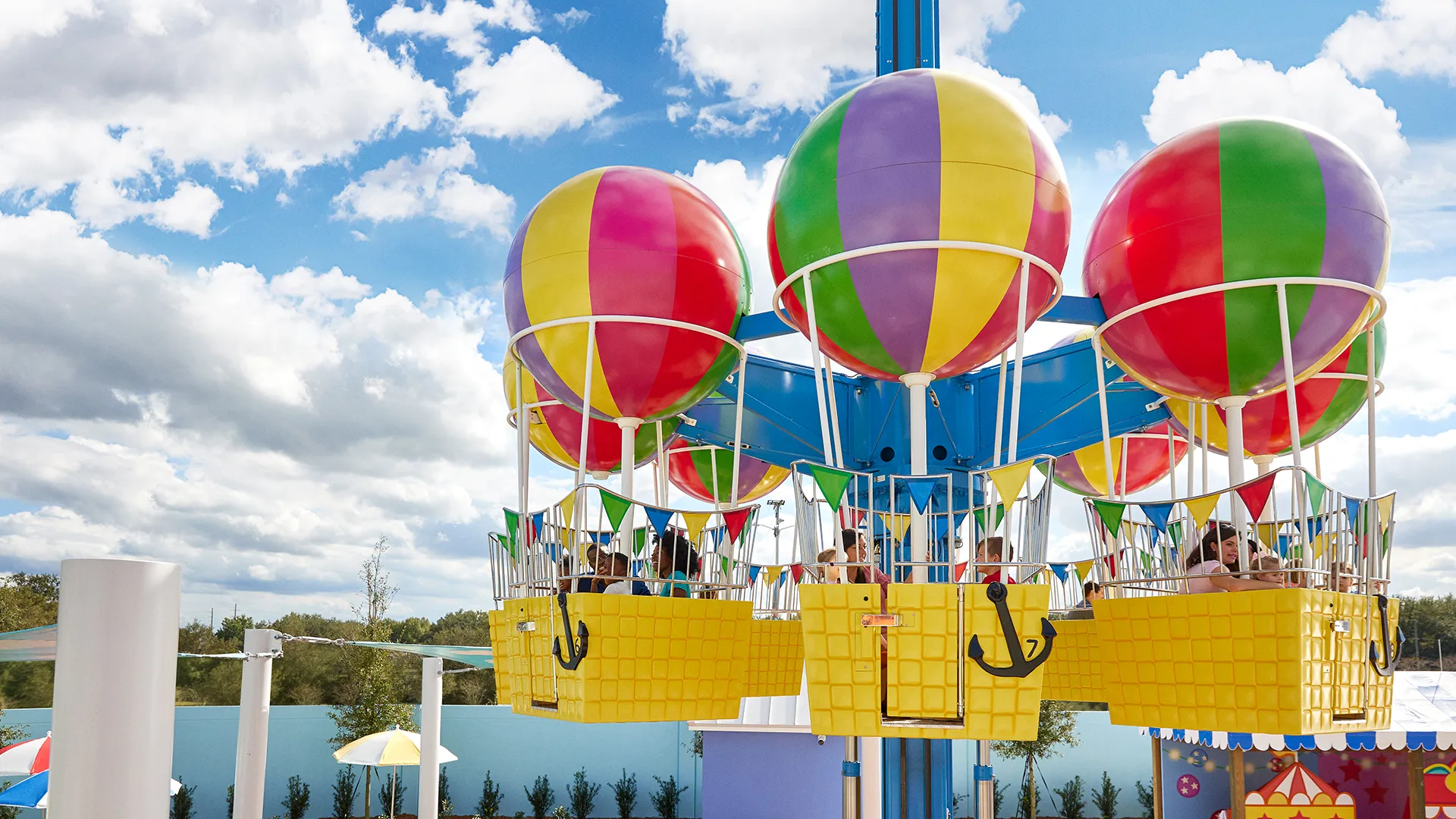 Padres e hijos disfrutan del paseo en el Globo de Peppa Pig en Peppa Pig Theme Park en Dallas Fort Worth. La familia sonríe y se ríe mientras vuelan suavemente por el aire, admirando la colorida y divertida atmósfera del parque desde las alturas.