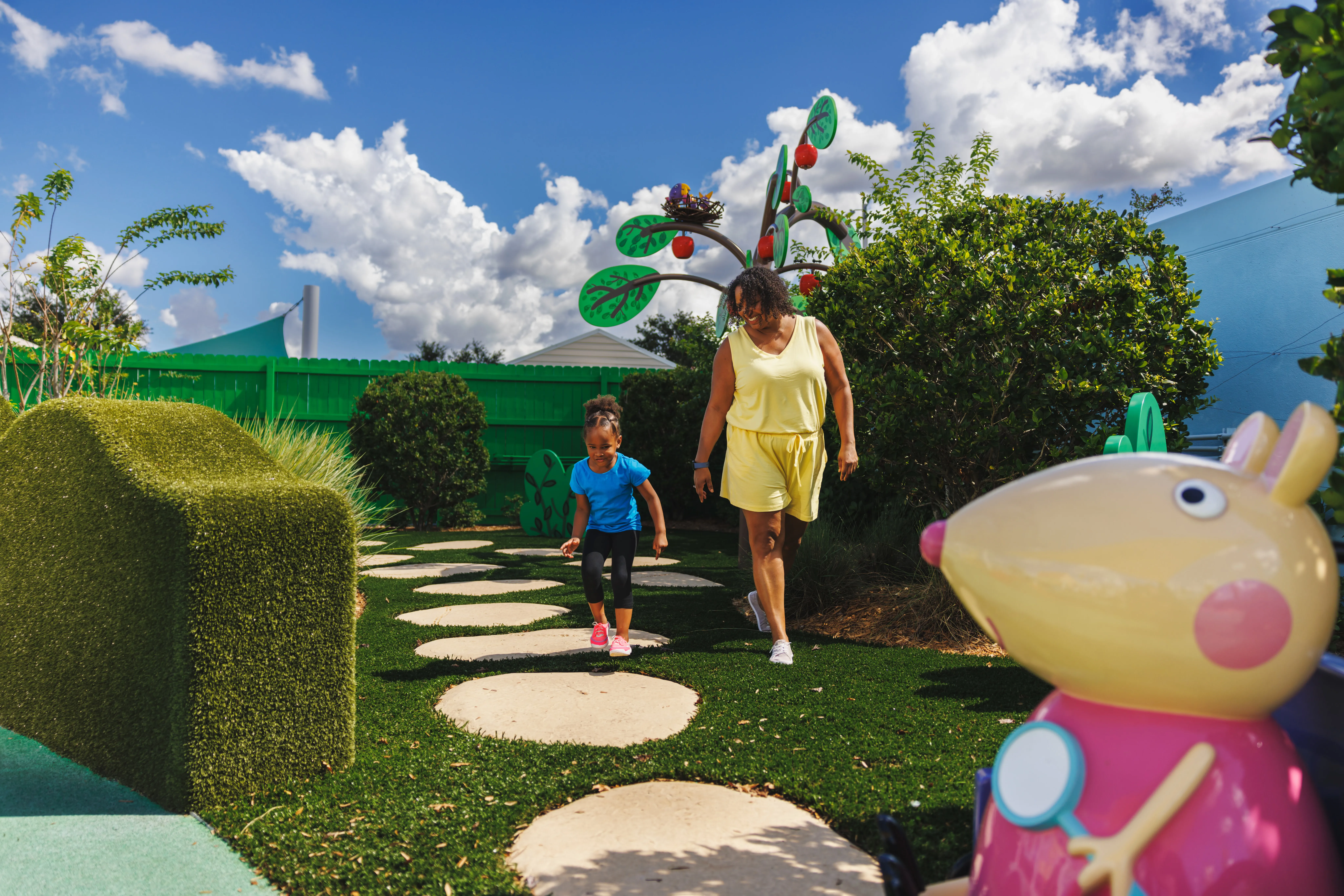 Una madre y su hija juegan juntos en la atracción del Sendero Natural de Madame Gazelle en el Peppa Pig Theme Park en Dallas Fort Worth. Disfrutan explorando el sendero natural colorido e interactivo, descubriendo características divertidas mientras están rodeados por la vibrante atmósfera al aire libre del parque.