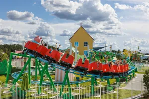 Los visitantes disfrutan montando la montaña rusa de Daddy Pig en Peppa Pig Theme Park en Dallas Fort Worth. Los emocionados pasajeros sonríen y se ríen mientras experimentan los emocionantes giros y vueltas de la montaña rusa, rodeados por la vibrante y juguetona atmósfera del parque.