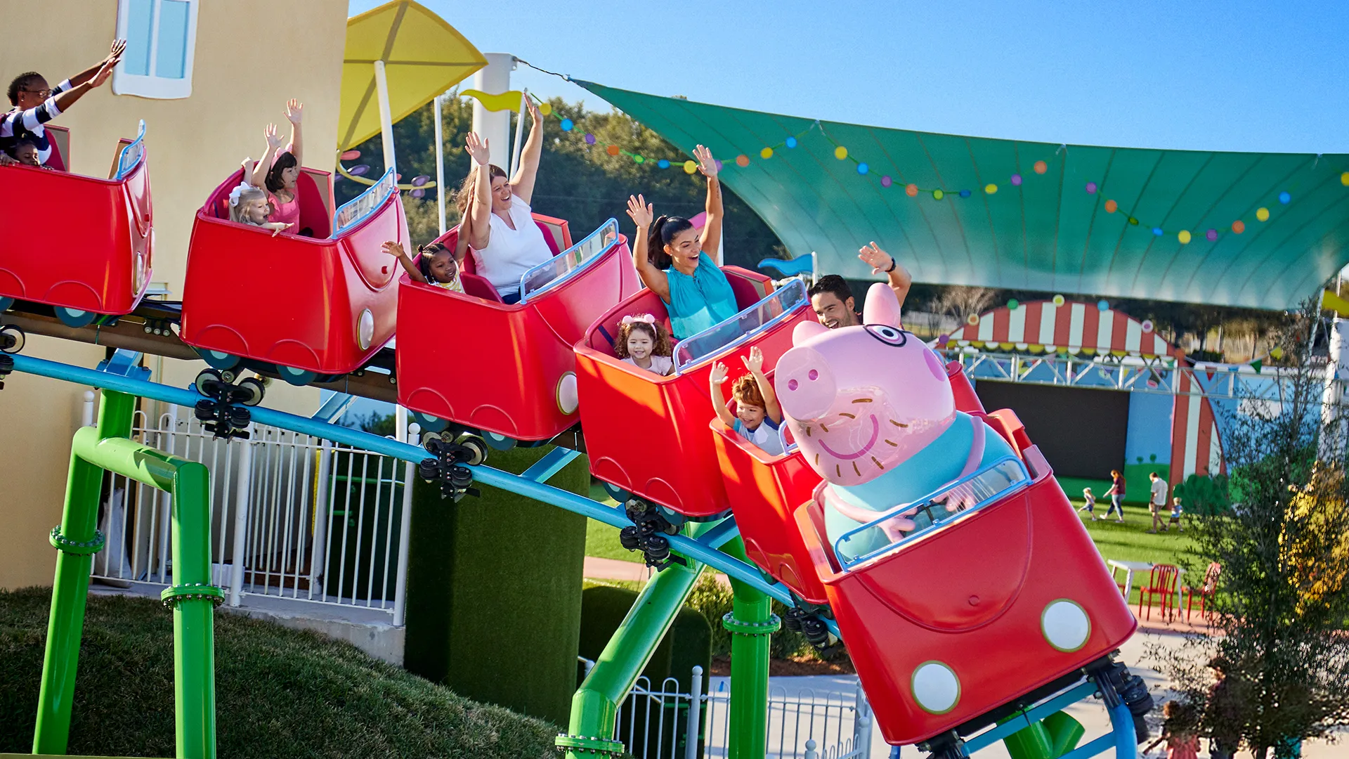 Los visitantes disfrutan de la emoción de la montaña rusa de Daddy Pig en Peppa Pig Theme Park en Dallas Fort Worth, sonriendo y riendo mientras viven juntos la emocionante experiencia.