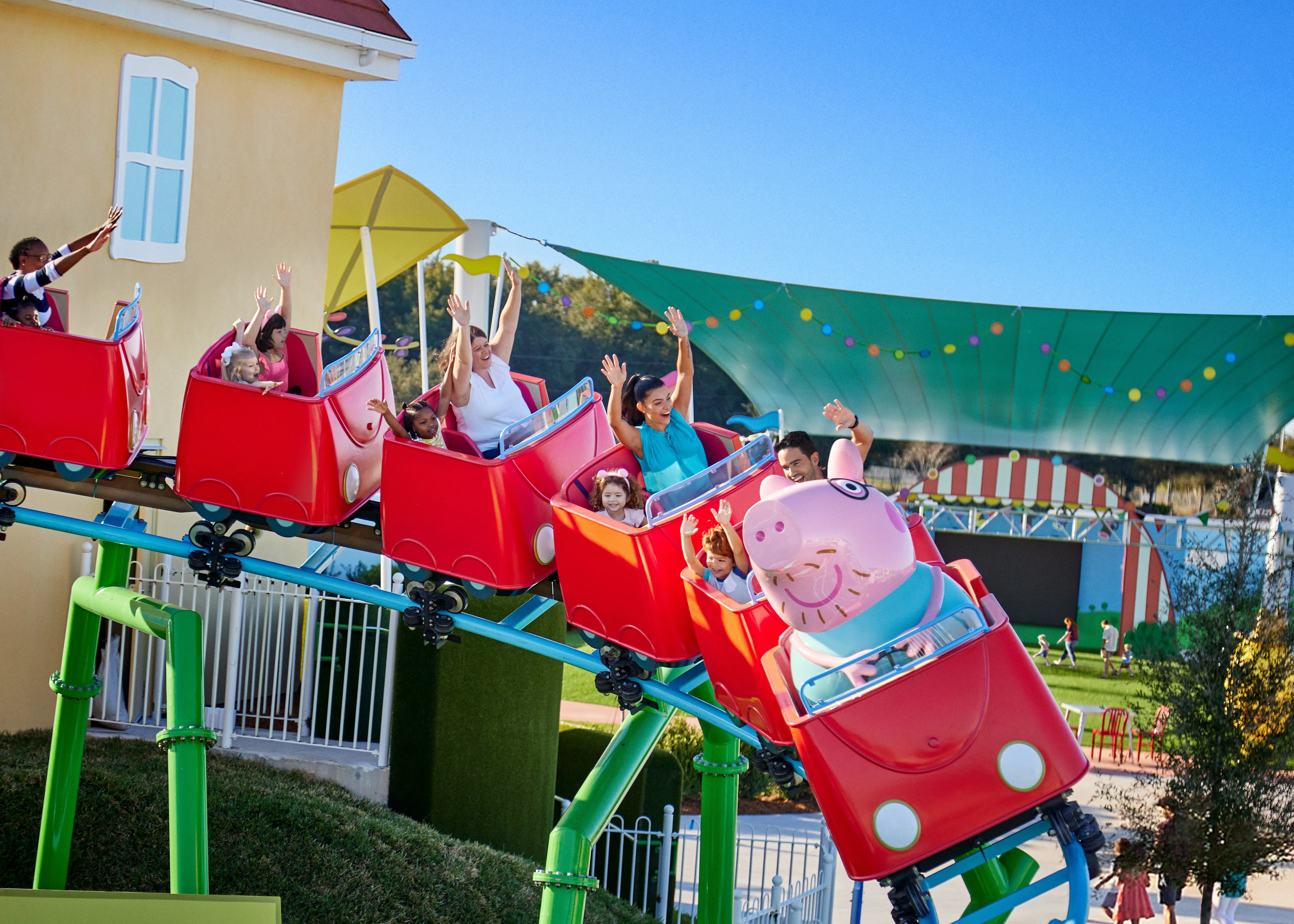 Los visitantes disfrutan de la emoción de la montaña rusa de Daddy Pig en Peppa Pig Theme Park en Dallas Fort Worth, sonriendo y riendo mientras viven juntos la emocionante experiencia.