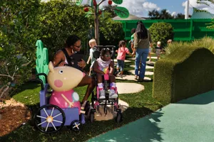 Las familias disfrutan explorando la atracción del Sendero Natural de Madame Gazelle en el Peppa Pig Theme Park en Dallas Fort Worth, interactuando con las coloridas características en un animado entorno al aire libre.